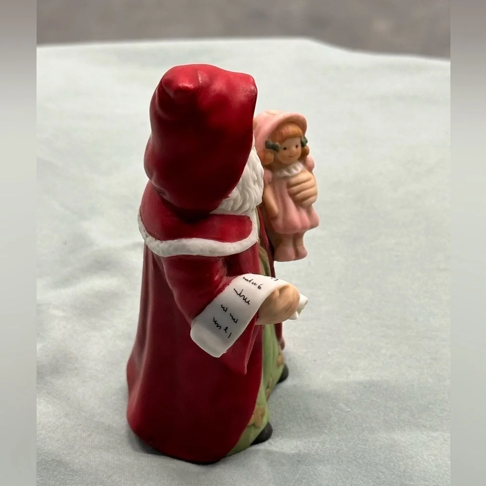 Small porcelain Santa figure.Santa carries a doll and a copy of his list.